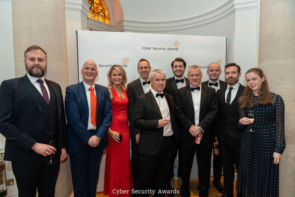 Guests in black tie at the Cyber Security Awards ceremony, gathered at the awards backdrop